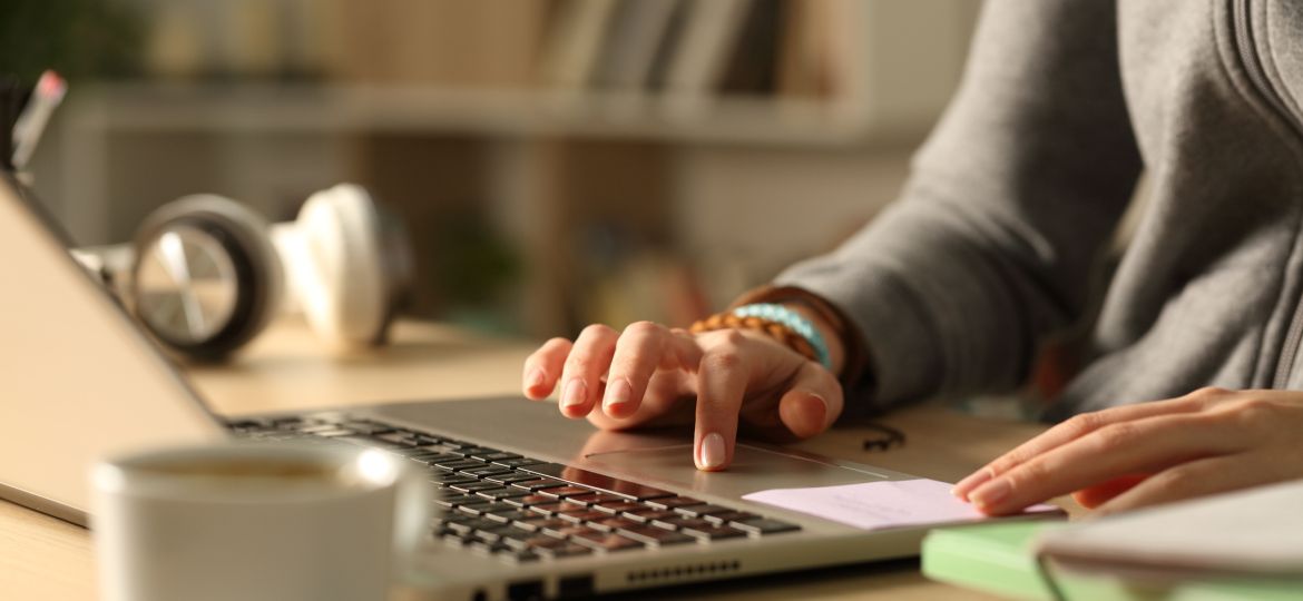 Student hands using touchpad on laptop at night