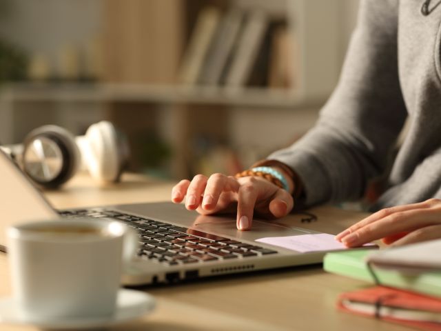 Student hands using touchpad on laptop at night