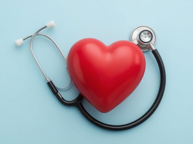 Heart Checkup: A conceptual close-up, top-down composition displays a red heart encircled by a stethoscope, signifying health and medical care on a blue background.
