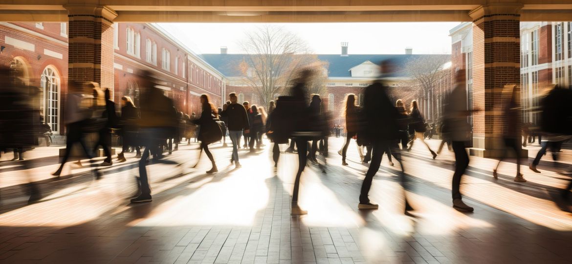 Crowd of students walking through a college campus on a sunny day, motion blur